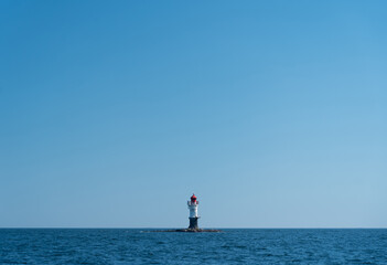 navigation buoy or small beacon on tiny island in the calm blue sea.