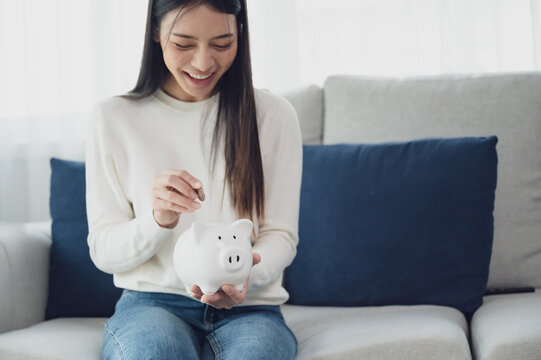 Asian woman putting coin in piggy bank. Save money and investment concept