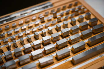 Set of metal weight reference standards on wooden tray