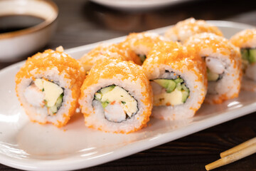 Sushi roll set with shrimp, flying fish reo, avocado and cucumber on a white plate. Japanese cuisine