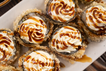 Roll, cream cheese and sweet sauce, traditional Japanese food on white dish, Japanese food style, Sushi Menu, salmon sushi roll, top view