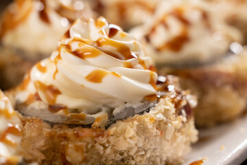 close-up of tempura sushi roll with salmon and shrimp garnished with cream cheese on top. Macro shot. Japanese cuisine, sushi menu, restaurant menu