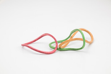 Three rubber bands in yellow, green and red in abstract shape on a white background.