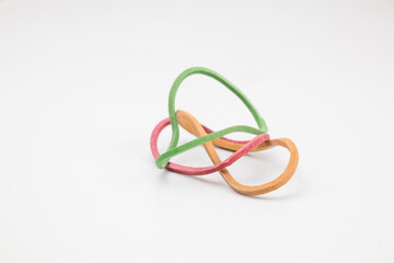 Three yellow, green, and red rubber bands in an abstract shape.