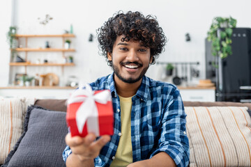 Happy man giving a gift. Anniversary, valentines day or birthday online concept. Young Asian using webcam to congratulate a loved one