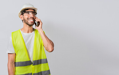 Young builder engineer in vest talking on cell phone isolated. Civil engineer concept talking on cellphone isolated, Smiling engineer talking on the phone isolated with copy space