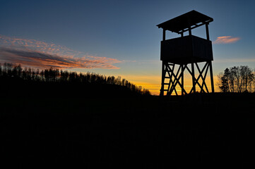 Fototapeta na wymiar Hunting tower silhouette on sunset in blue and orange