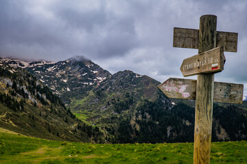Trail indication signs with snowy mountains in the background near Ayes lake the French Pyrenees mountain range
