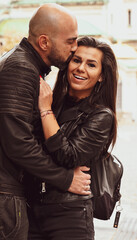 Romantic couple  in casual outfits toasting with champagne  outdoors and  posing on streets of european city. Beautiful woman clinking with her husband.Happy couple with a glass of wine 