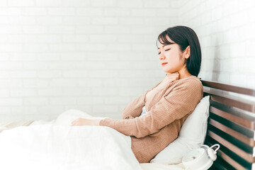 ベッドルームで喉・扁桃腺・首に悩む日本人女性

