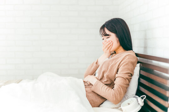 ベッドルームで腹痛・生理痛・悪阻に悩む日本人女性
