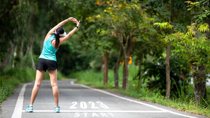 The start into the new year 2023. Start up of runner woman running on nature race track go to Goal...