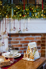 A small gingerbread house with icing, decorated for Christmas. Backery for serving a festive table creates Festive mood