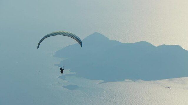 The alone paraglider is flying above the coastal landscape of sea and island in Oludeniz, Turkey. 
