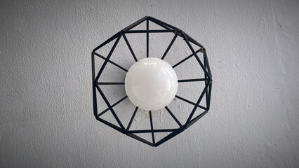A white bulb or lamp with black steel ornament that is mounted on the wall for vintage background and decoration inspiration