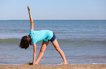 girl while performing gymnastic exercises near the sea