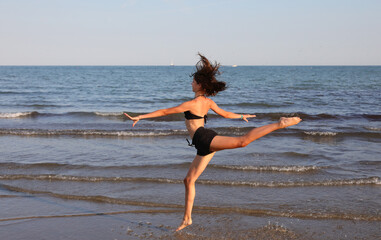 young girl with long legs jumps by the sea
