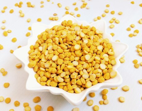 Split chickpeas legume dal chana Bengal gram lentils pulse yellow organic dahl food full with protein harbara kabuli channa daal uncooked Egyptian splitchickpea spread on surface closeup image photo 