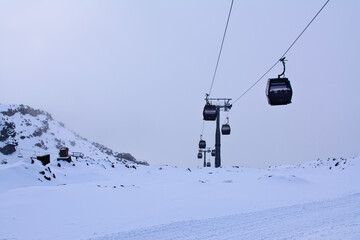 Fototapeta na wymiar Cable cars going up and down snow blanketed slopes of the mountain while a snow storm building up. Mt Ruapehu, Whakapapa Sky Field, New Zealand