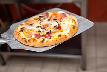 chef baker making pizza at kitchen. Put on landing shovel and send it to the oven.