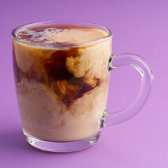 Transparent cup of coffee with cream forming a beautiful pattern