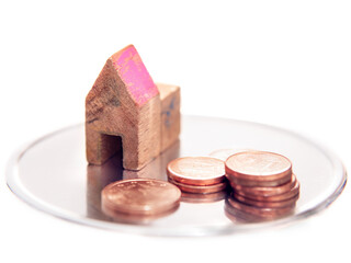 Toy small house and coins on white background. Selective focus.