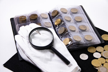 Album with coins, white gloves and a magnifying glass