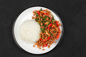 Stir fried Thai basil with minced pork and  in white plate on black table.