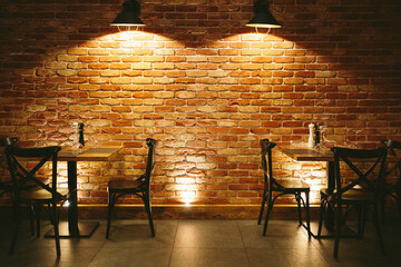 Restaurant dining tables against brick wall.