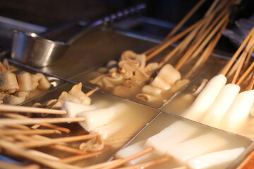Bamboo fish skewers resting in liquid - South Korean street food