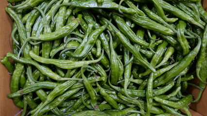 Full frame image of fresh green raw chilis in cardboard box