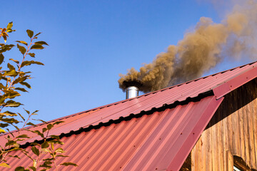 Thick smoke from a coal stove against the blue sky, the concept of environmental protection and...