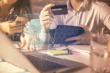 Double exposure of man and woman on-line shopping holding a credit card and fingerprint hologram...