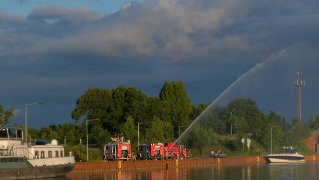 Young firefighters practice hosing down water on the banks of a water canal in Germany.