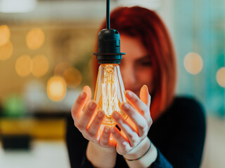 Symbolic photo of a business woman holding a light bulb in a modern office