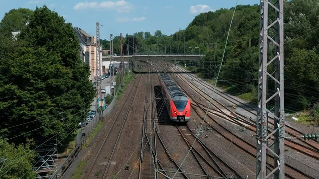 An arriving red passenger train at Wuppertal station in Germany. View from above.