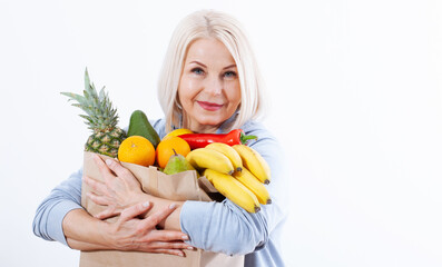 Happy woman with blond hair and beautiful smile holds many fruits oranges, lemon, bananas, kiwi, avocado, pears and pineapple in her hands for a healthy diet with vitaminswith.