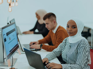 Group of multi-ethnic colleagues working on desktop computers, laptop and sharing their ideas in a modern office space.Young influencers work on online marketing projects.