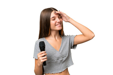 Teenager singer girl picking up a microphone over isolated background smiling a lot