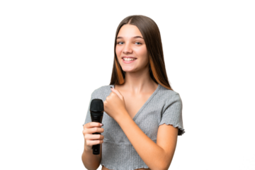 Teenager singer girl picking up a microphone over isolated background celebrating a victory