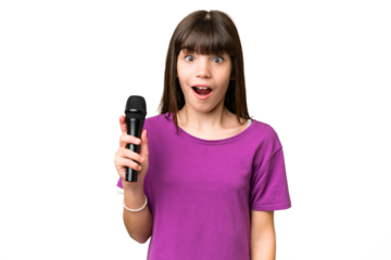 Little singer girl picking up a microphone over isolated background with surprise and shocked facial expression