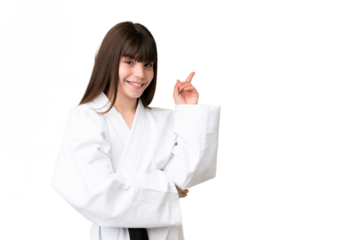 Little Caucasian girl doing karate over isolated background pointing finger to the side