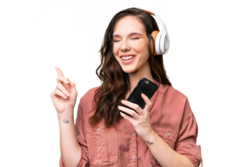Young caucasian woman over isolated background listening music with a mobile and singing