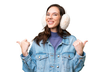 Young caucasian woman wearing winter muffs over isolated background with thumbs up gesture and...