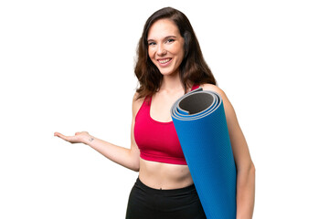 Young sport woman going to yoga classes while holding a mat over isolated background extending...