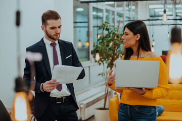 The boss of the company talking to his employee while she shows him the final report on the laptop