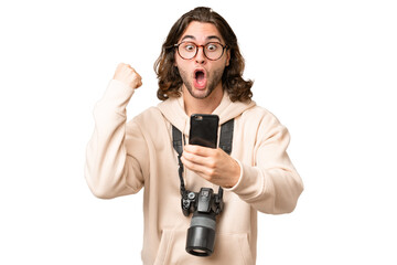 Young photographer man over isolated background surprised and sending a message