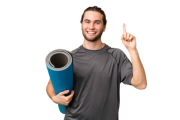 Young sport man going to yoga classes while holding a mat over isolated background pointing up a great idea