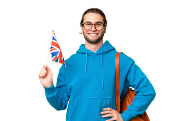 Young handsome man holding an United Kingdom flag over isolated background posing with arms at hip and smiling