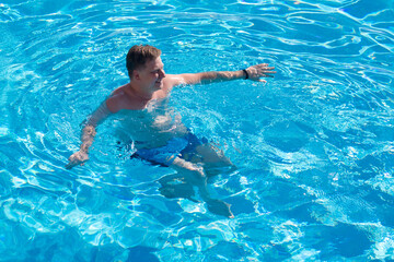 An adult European man happily swims pool. Luxury holiday concept.